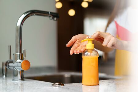 Close up of a woman washing her hands in a kitchen sink at homeの写真素材