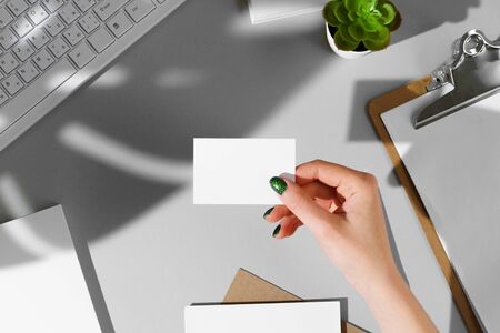 Woman's hand giving businesscard above the working table, copy spaceの写真素材