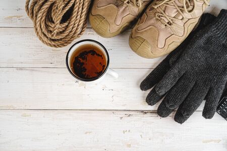 Hiking boots with equipment for hiking, cup of tea on wooden board close upの写真素材