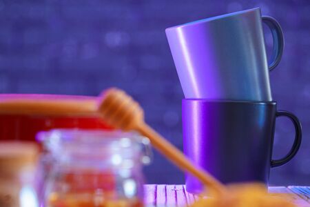 Wooden honey dipper on kitchen table with kitchenware