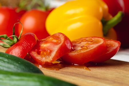 Cut tomatoe pieces on wooden board in kitchen close upの写真素材