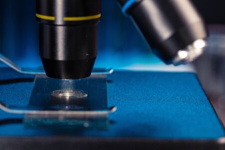 Laboratory microscope with lenses close up against dark background
