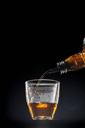 Whisky pouring into a glass on black background, copy spaceの写真素材