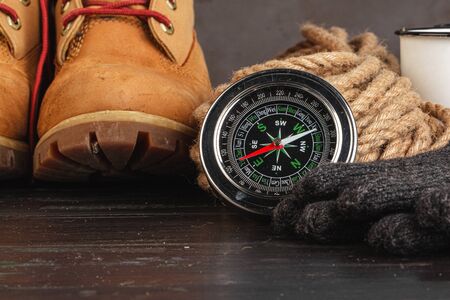Compass surrounded by mountain gear tools on wooden background