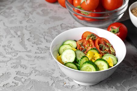 Ceramic bowl of tomato and cucumber salad on table, close upの写真素材
