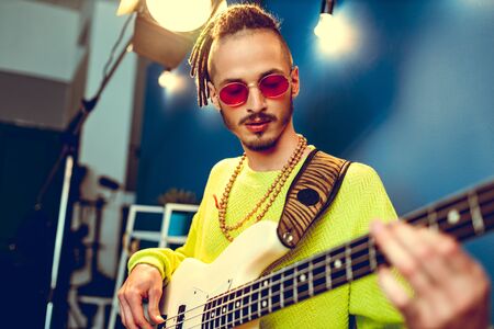 Cool guy with dreads practicing playing guitar at homeの写真素材