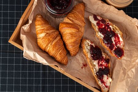 Fresh croissants with berry jam on dark wooden boardの写真素材