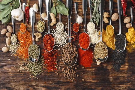 Spices in spoons on dark wooden background, top view, copy spaceの写真素材