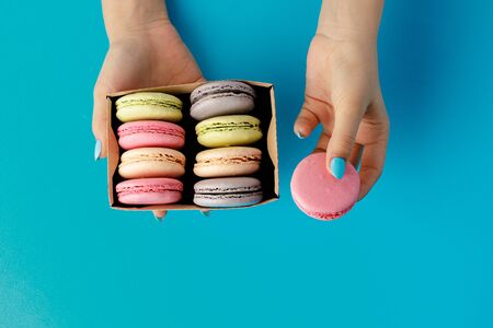 Womans hands holding box with colorful macaroon cookies