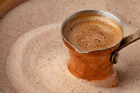 Copper turk with coffee brewing in sand close up.の写真素材