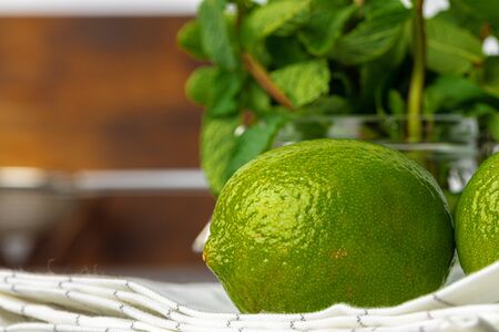 Two lime fruits on white napkin and bunch of mint on kitchen tableの写真素材