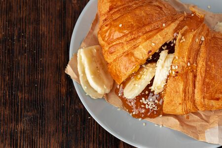 Half cut croissant with chocolate paste and sliced bananasの写真素材