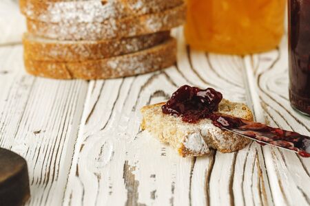 Slice of fresh bread with butter and jam on wooden tableの写真素材