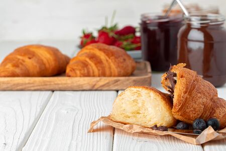 Fresh croissant decorated with berries on white wooden board close upの写真素材