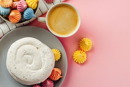 White meringue cookie on pink background with colorful mini meringuesの写真素材