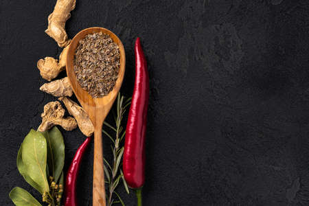 Top view of wooden spoon and spices on dark black surfaceの写真素材