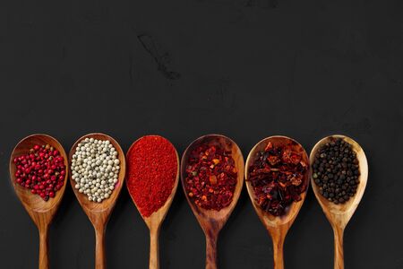 Wooden spoons with various spices on black background with copy spaceの写真素材