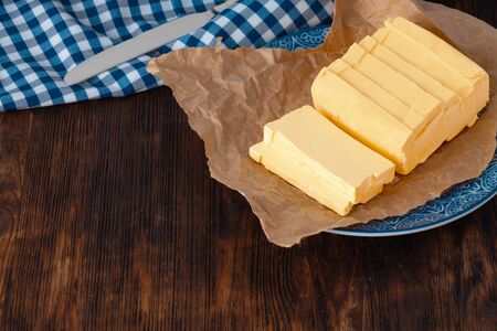 Cut butter on plate with blue towel on kitchen table. close up.