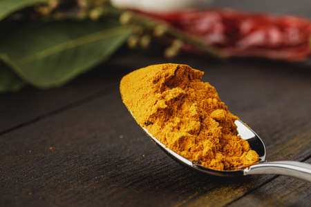 Spoon with spices on dark wooden table close upの写真素材