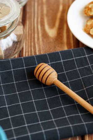 Wooden honey dipper on kitchen table with kitchenwareの写真素材