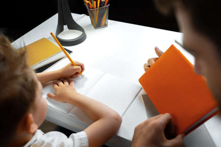 Father helping his little son with school homework close up
