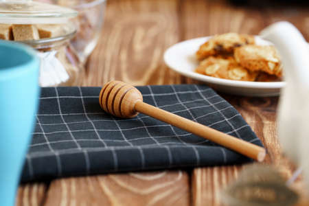 Wooden honey dipper on kitchen table with kitchenwareの写真素材