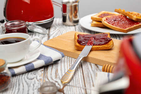 Crispy toasts covered with fruit jam served on kitchen table, close up