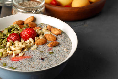 Chia pudding with strawberry and pumpkin seeds on wooden table with apricotsの写真素材