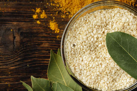 White sesame in glass bowl on wooden table, close up