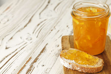 Slice of bread covered with fruit jam on wooden board close upの写真素材