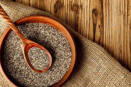 Chia seeds in a bowl with wooden spoonの写真素材