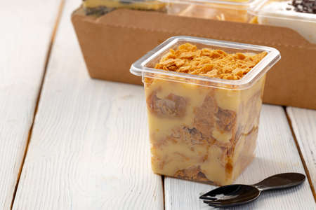 Creamy dessert in a plastic box on wooden table close upの写真素材