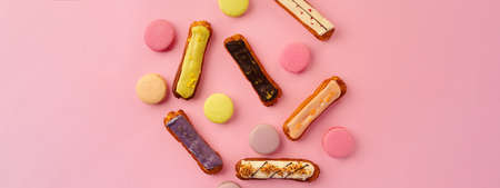 Top view of eclair cakes and macaroon cookies on pink backgfround with copy space