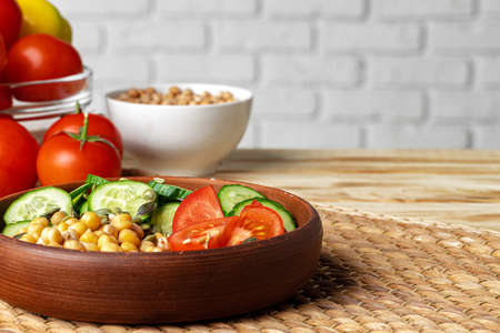 Clay plate of chickpeas and cut cucumbers and tomatoes. Healthy eating saladの写真素材