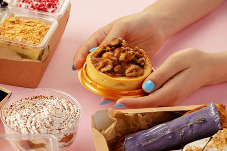 Female hands holding dessert in hands among fresh confectionary, close up