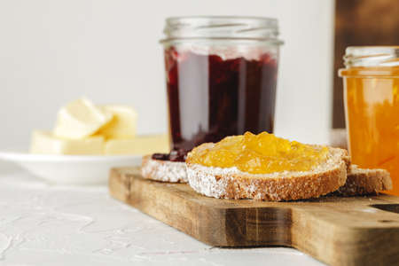 Slice of fresh bread with butter and jam on wooden table