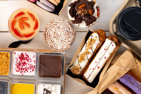 Assortment of desserts in boxes on white wooden background top viewの写真素材
