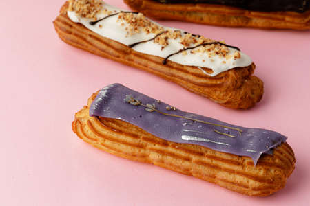 Fresh eclair cakes on pink background close up, copy space