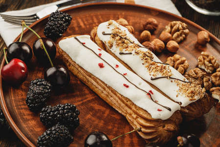 Two eclairs decorated with berries and nuts close upの写真素材