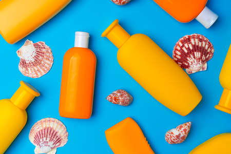 Sunscreen cream bottles with sea shells on blue background close upの写真素材