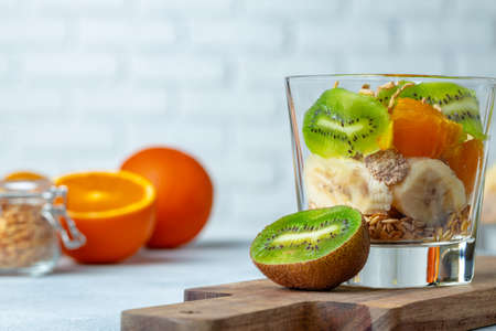 Glass with fruit pieces and oatmeal muesli on wooden board close upの写真素材