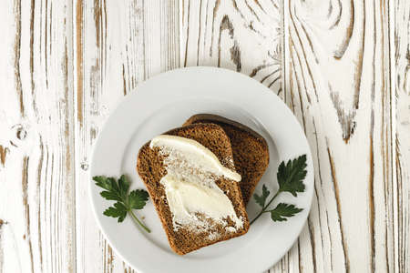 Buttered slice of rye bread on wooden tableの写真素材