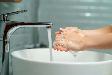 Close up of a woman washing her hands in a bathroom sink at home