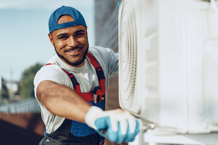 Young black man repairman checking an outside air conditioner unitの写真素材