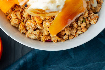 Bowl of granola with youghurt and sliced fruits close up
