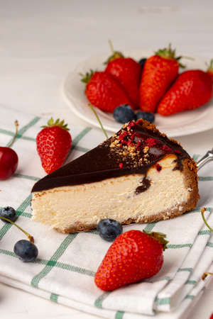 Piece of cheesecake with chocolate top and fresh berriesの写真素材