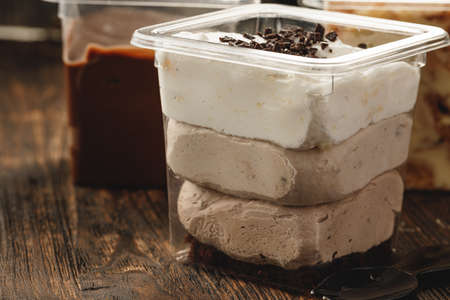 Creamy dessert in a plastic box on wooden table