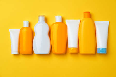 Collection of sunscreen cream bottles on yellow background close upの写真素材
