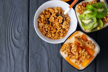Tasty breakfast with granola, yoghurt and fruits in a glass bowl on wooden tableの写真素材