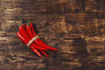 Red hot chili peppers on dark wooden table, copy space